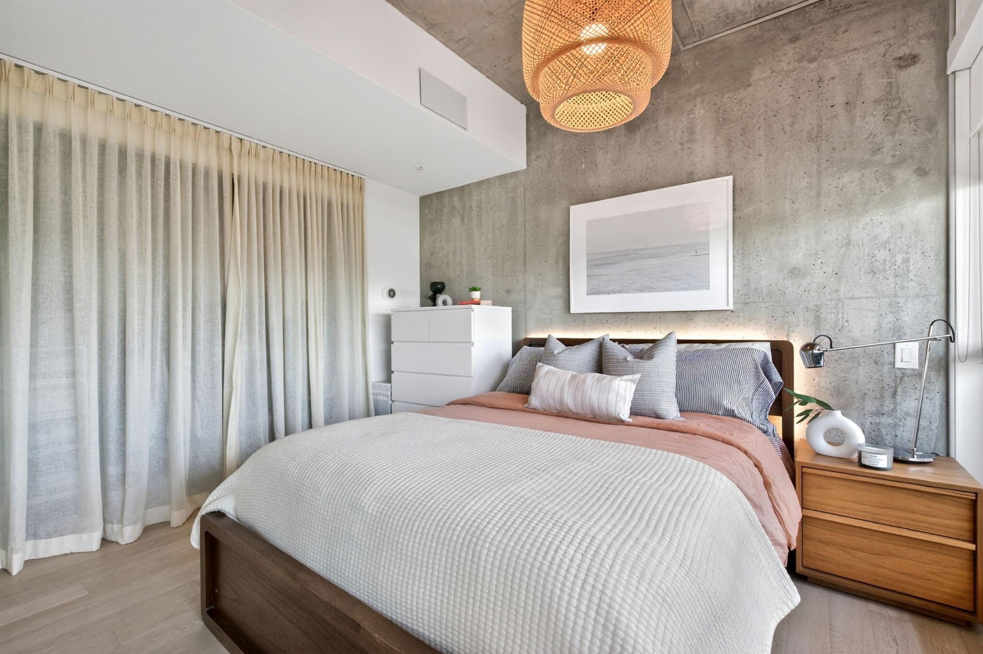 Primary bedroom with sheer curtains and concrete accent wall