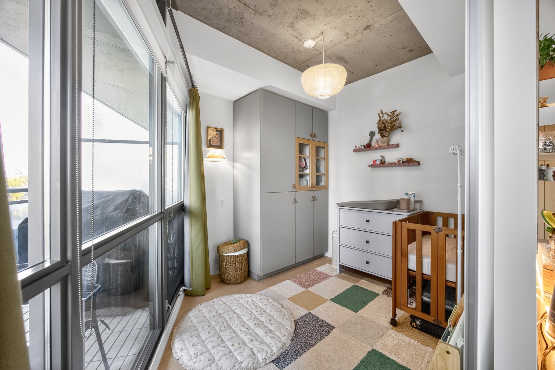 Second bedroom set up as nursery with built-in storage and concrete ceiling